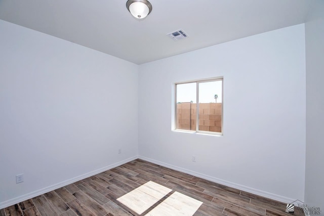 spare room featuring baseboards, wood finished floors, and visible vents