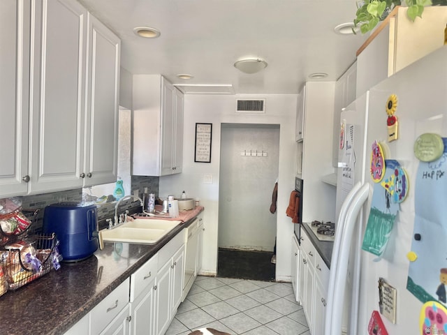 2681 S Walnut Ave, Yuma, AZ 85364 - kitchen with white appliances, light tile patterned floors, white cabinets, dark countertops, and tasteful backsplash