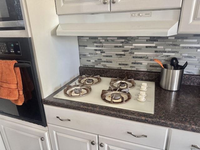 2681 S Walnut Ave, Yuma, AZ 85364 - kitchen view of black oven, under cabinet range hood, stainless steel microwave, backsplash, and white gas cooktop