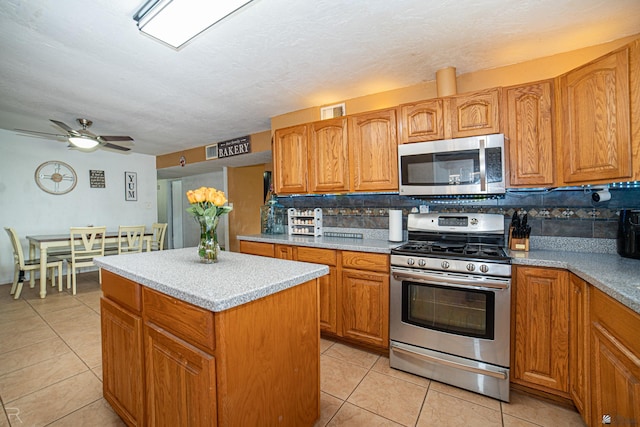 2556 W 14th St, Yuma, AZ 85364 - kitchen featuring stainless steel appliances, a kitchen island, light tile patterned flooring, and backsplash