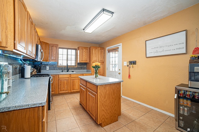 2556 W 14th St, Yuma, AZ 85364 - kitchen with black range with electric cooktop, stainless steel microwave, wine cooler, a textured wall, and a kitchen island