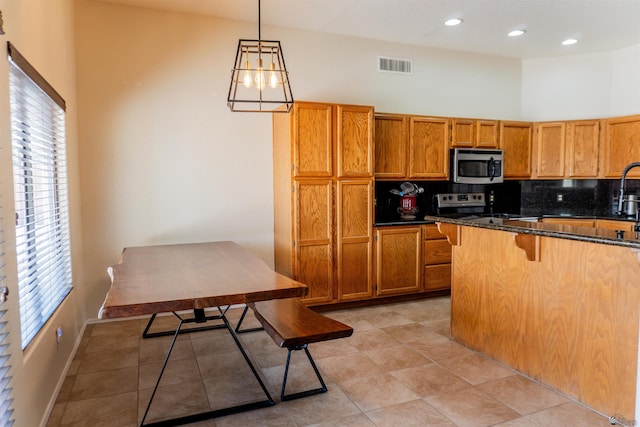 10453 S Del Rico, Yuma, AZ 85367 - kitchen with decorative backsplash, a kitchen breakfast bar, visible vents, brown cabinets, and stainless steel appliances
