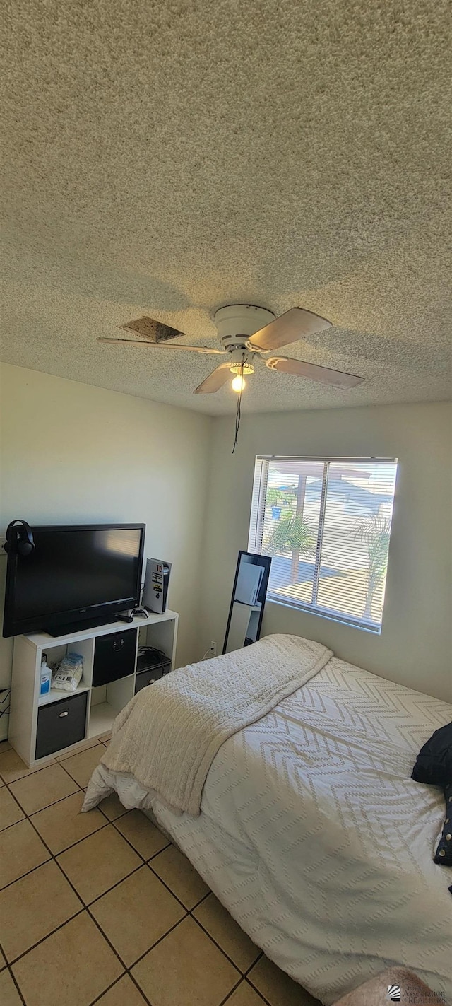 bedroom with a ceiling fan, a textured ceiling, and tile patterned flooring