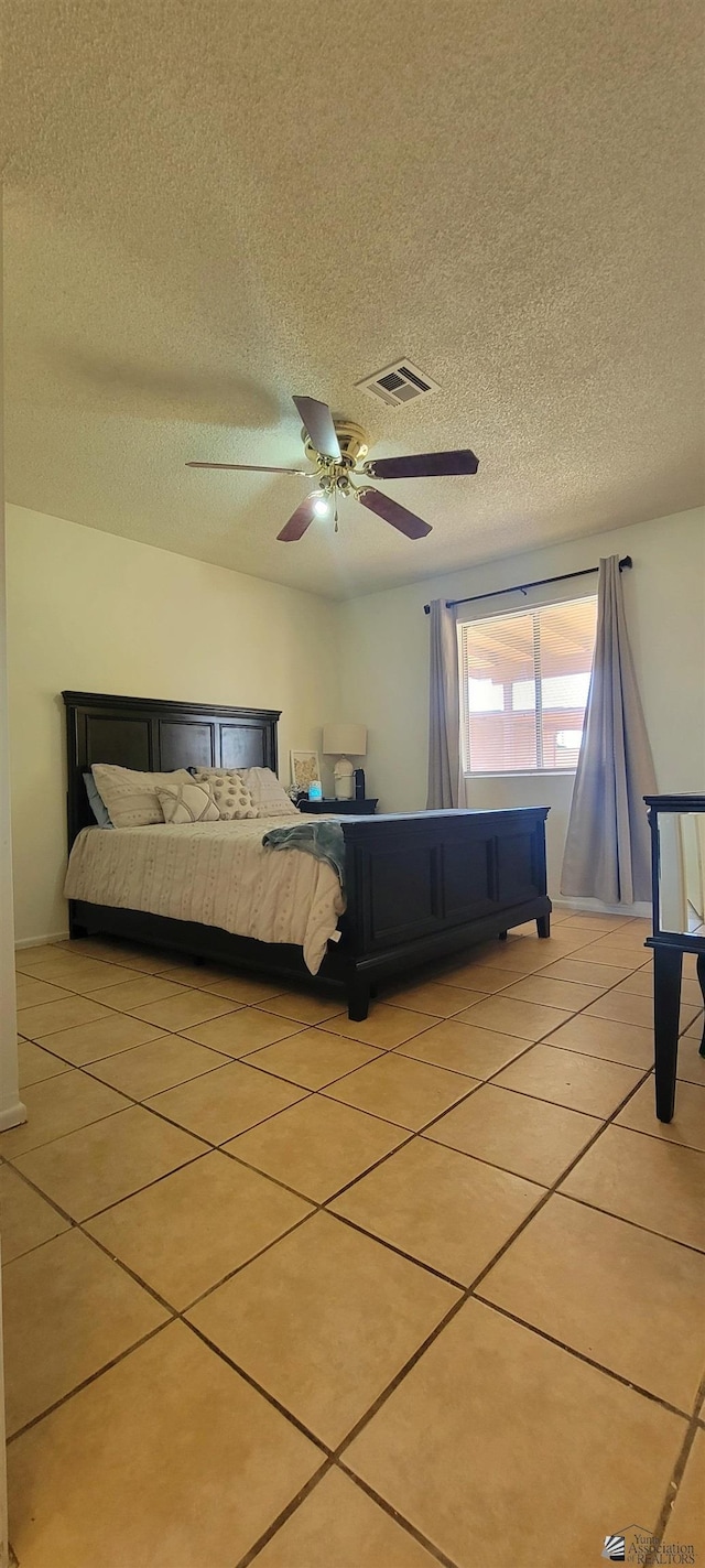 bedroom featuring light tile patterned floors, a ceiling fan, a textured ceiling, and visible vents