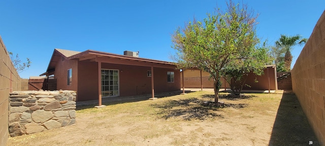 rear view of house with a fenced backyard and stucco siding