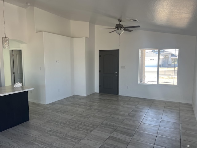 tiled empty room with ceiling fan, lofted ceiling, and a textured ceiling