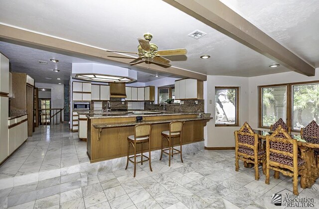 1376 S Hettema St, Yuma, AZ 85364 - kitchen with stainless steel microwave, decorative backsplash, light marble finish floors, a peninsula, and baseboards