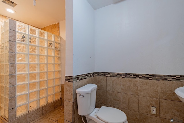 2320 S Maple Ave, Yuma, AZ 85364 - bathroom with tile walls, a walk in shower, toilet, a wainscoted wall, and tile patterned floors