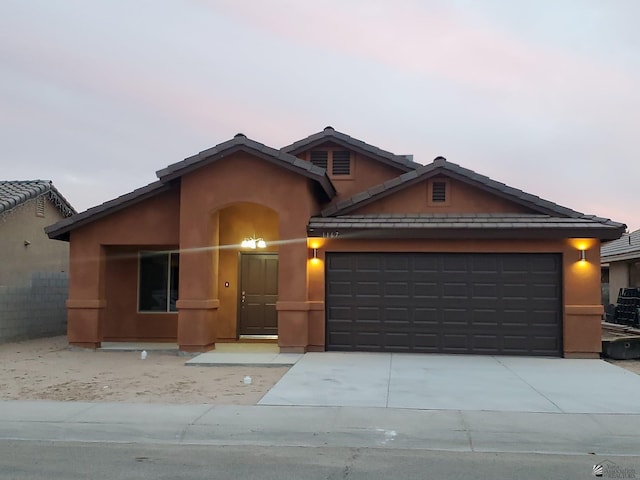 ranch-style house with concrete driveway, an attached garage, and stucco siding