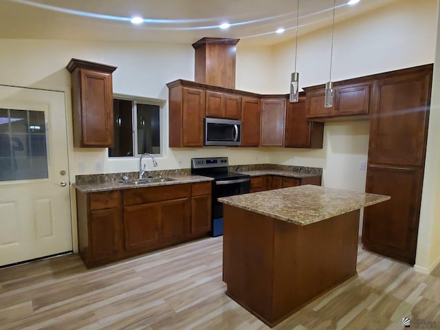 kitchen with a sink, dark stone counters, appliances with stainless steel finishes, and light wood-style flooring