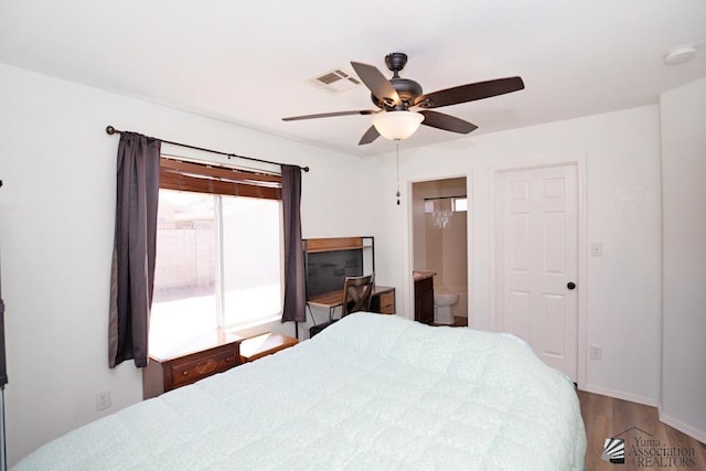 bedroom with visible vents, ensuite bath, wood finished floors, and ceiling fan