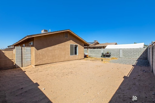 rear view of property with a fenced backyard and stucco siding
