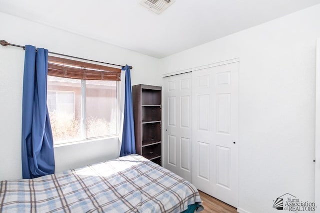 bedroom featuring visible vents, wood finished floors, and a closet