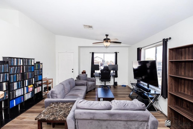 living room with a ceiling fan, visible vents, wood finished floors, and vaulted ceiling