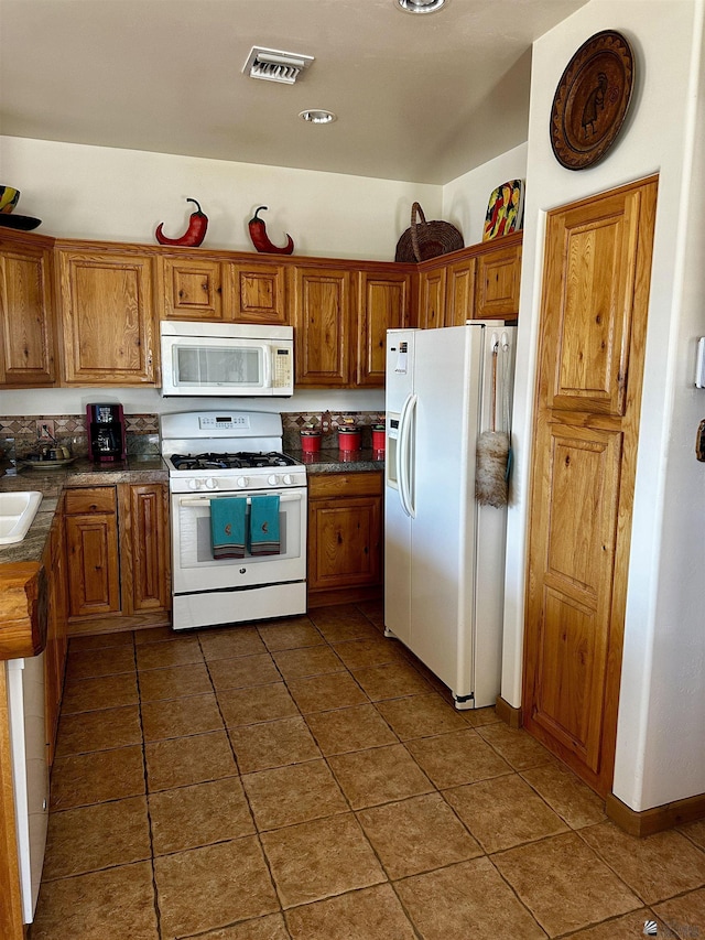 12696 E 45th Ln, Yuma, AZ 85367 - kitchen featuring dark countertops, white appliances, brown cabinetry, dark tile patterned floors, and visible vents