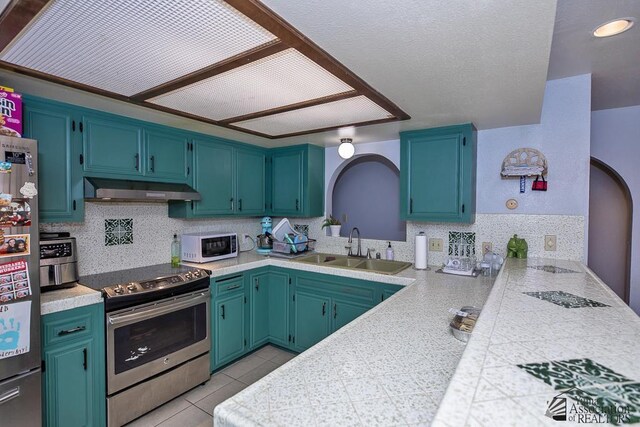 543 E 25th St, Yuma, AZ 85365 - kitchen with appliances with stainless steel finishes, under cabinet range hood, tasteful backsplash, a peninsula, and light countertops