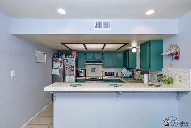 543 E 25th St, Yuma, AZ 85365 - kitchen with green cabinets, stainless steel appliances, under cabinet range hood, a peninsula, and light countertops
