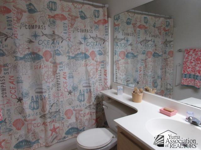10646 S Via Salida, Yuma, AZ 85367 - bathroom with vanity, toilet, and shower / bathtub combination with curtain