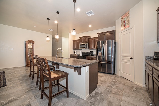 4387 W 24th Pl, Yuma, AZ 85364 - kitchen with stainless steel appliances, dark brown cabinets, a kitchen breakfast bar, a kitchen island with sink, and dark stone counters