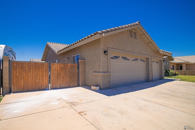 4387 W 24th Pl, Yuma, AZ 85364 - view of home's exterior featuring an attached garage, concrete driveway, a gate, a tile roof, and stucco siding
