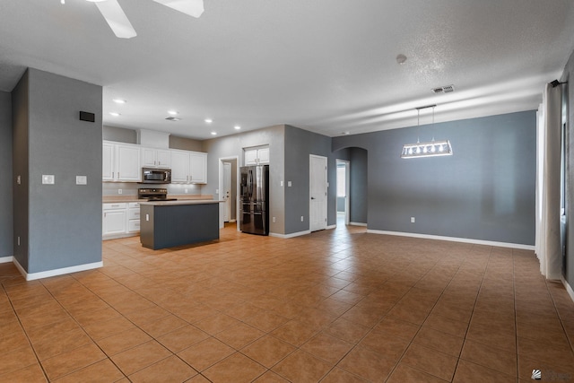 12170 E 33rd Pl, Yuma, AZ 85367 - kitchen with stainless steel appliances, open floor plan, arched walkways, white cabinetry, and light tile patterned flooring