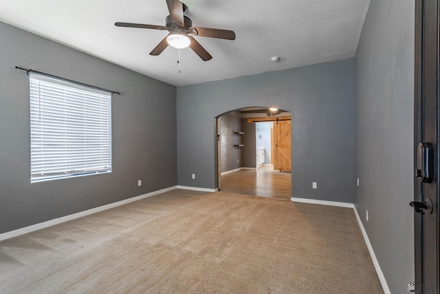 12170 E 33rd Pl, Yuma, AZ 85367 - empty room with arched walkways, carpet, a barn door, and a ceiling fan