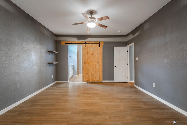12170 E 33rd Pl, Yuma, AZ 85367 - unfurnished bedroom featuring a barn door, light wood-style flooring, and baseboards