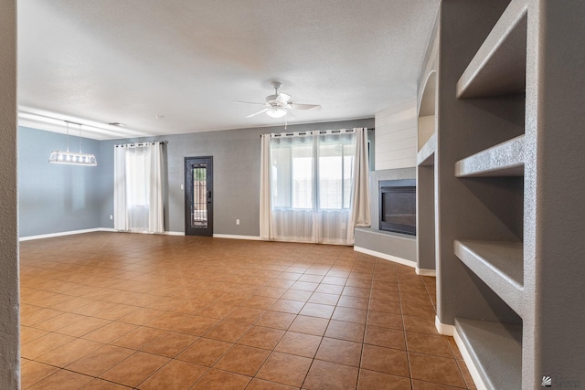 12170 E 33rd Pl, Yuma, AZ 85367 - unfurnished living room with tile patterned flooring, a glass covered fireplace, ceiling fan, and baseboards