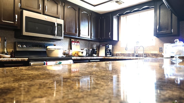kitchen with range with electric stovetop, stainless steel microwave, backsplash, and visible vents