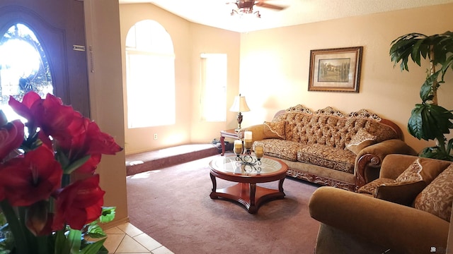 carpeted living area with tile patterned flooring, a ceiling fan, and vaulted ceiling