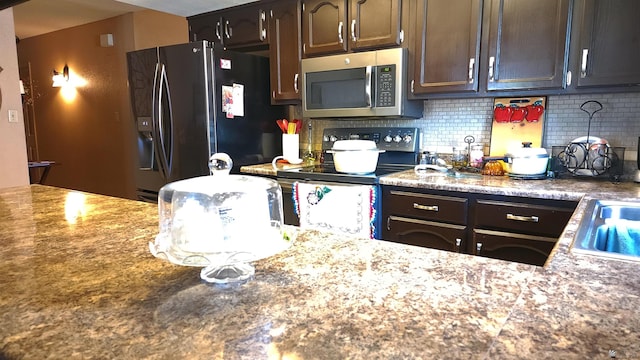 kitchen with backsplash, dark brown cabinetry, and appliances with stainless steel finishes