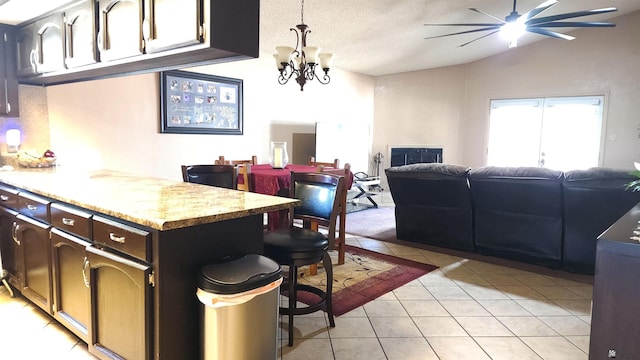 kitchen featuring light tile patterned flooring, open floor plan, vaulted ceiling, and ceiling fan with notable chandelier