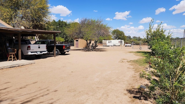 view of yard featuring a storage shed, fence, and an outbuilding