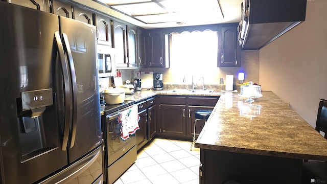 kitchen with a peninsula, appliances with stainless steel finishes, a healthy amount of sunlight, and a sink