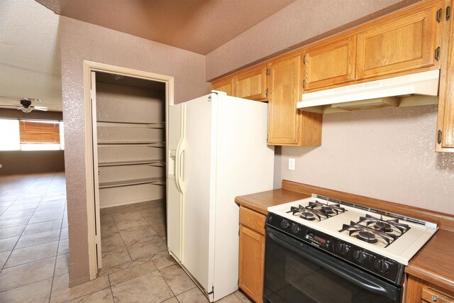 3023 W 26th St, Yuma, AZ 85364 - kitchen featuring range with gas stovetop, under cabinet range hood, white fridge with ice dispenser, ceiling fan, and light tile patterned floors