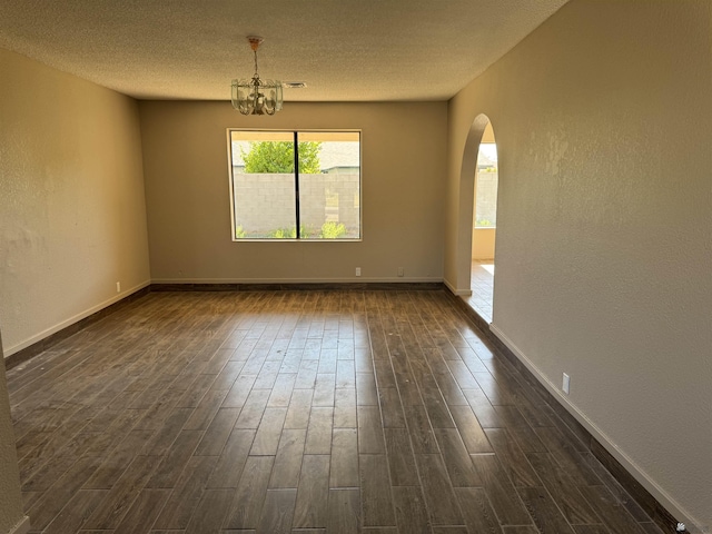 1276 S Pagent Ave, Yuma, AZ 85364 - empty room featuring dark wood finished floors, arched walkways, a chandelier, a textured ceiling, and a textured wall