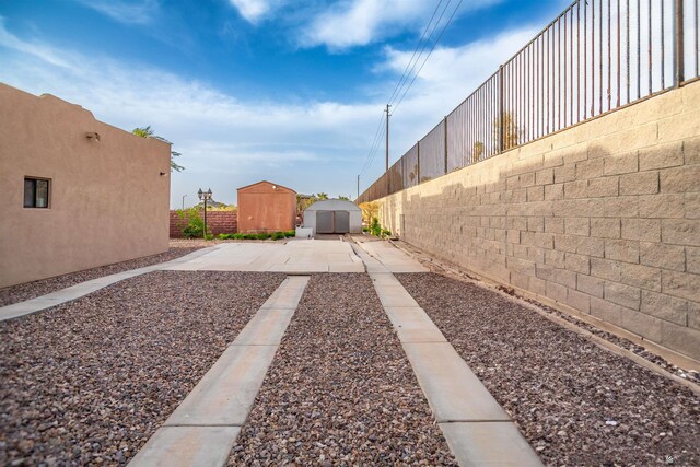 view of yard with a storage unit, a fenced backyard, an outbuilding, and a patio