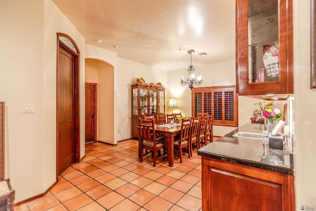 dining space featuring arched walkways, a chandelier, light tile patterned floors, and visible vents