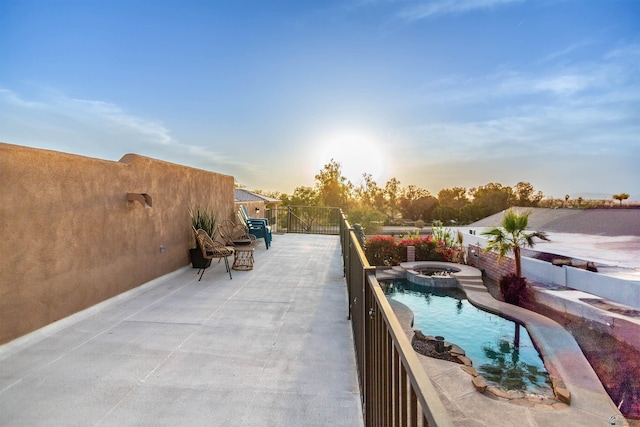 patio terrace at dusk featuring a pool with connected hot tub