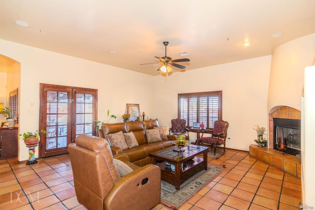 living area featuring ceiling fan, visible vents, arched walkways, a fireplace, and light tile patterned floors