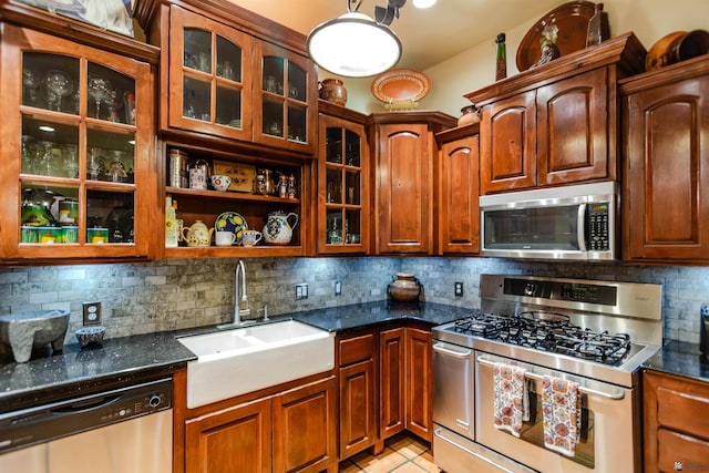 kitchen featuring light tile patterned flooring, a sink, stainless steel appliances, decorative backsplash, and glass insert cabinets