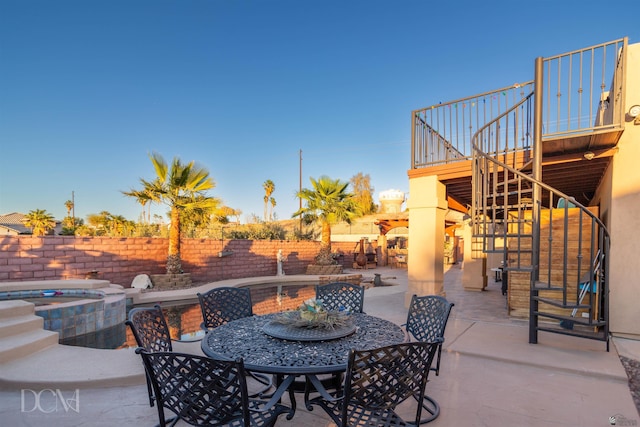 view of patio featuring stairs, outdoor dining space, a wooden deck, an in ground hot tub, and fence private yard