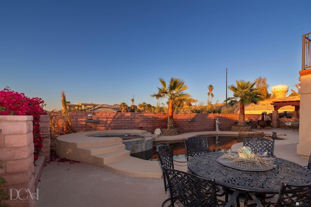 view of patio / terrace featuring a fenced backyard, a pool with connected hot tub, and outdoor dining space