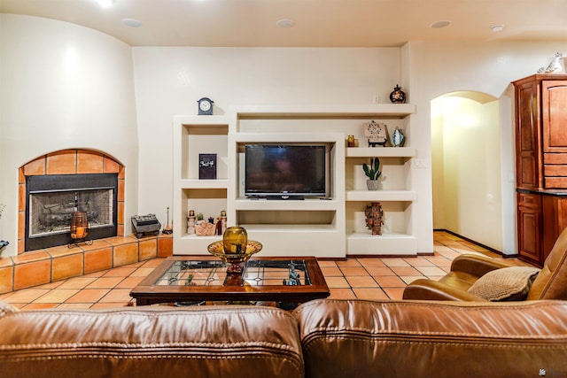 living room with arched walkways, built in shelves, light tile patterned flooring, and a fireplace