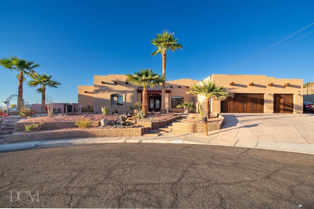 adobe home with a garage, stucco siding, and driveway