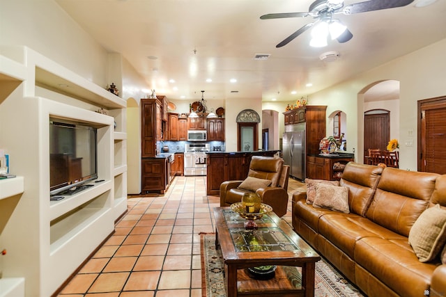 living area featuring visible vents, light tile patterned flooring, ceiling fan, recessed lighting, and arched walkways