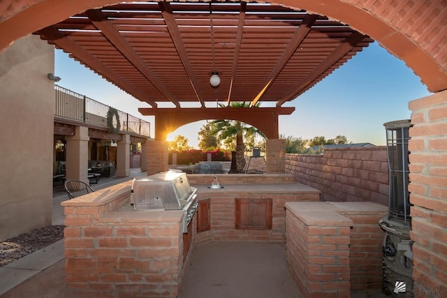 view of patio / terrace featuring fence, exterior kitchen, a pergola, and a grill