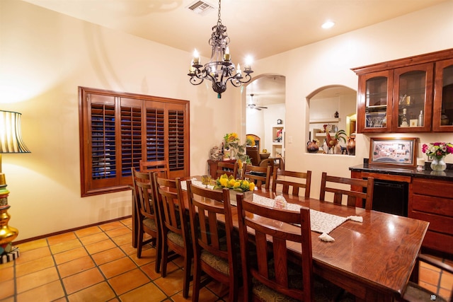 tiled dining room with arched walkways, ceiling fan with notable chandelier, and visible vents