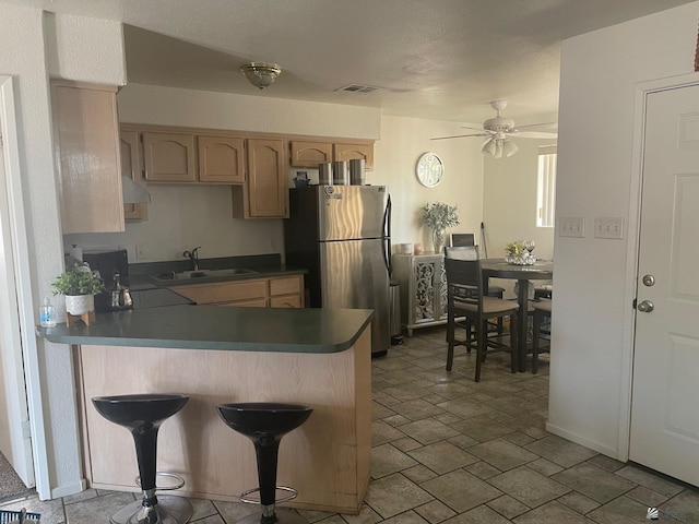 kitchen with ventilation hood, a sink, freestanding refrigerator, a ceiling fan, and visible vents
