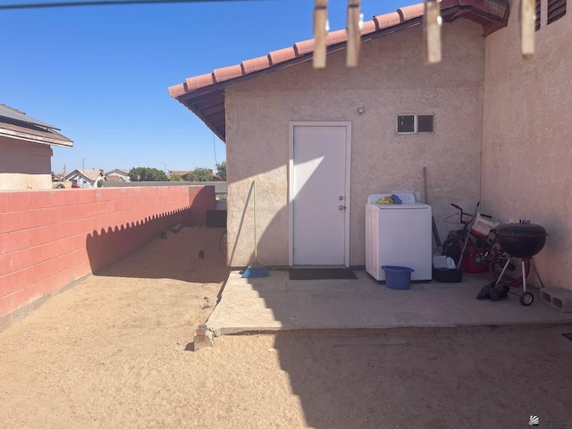 exterior space featuring stucco siding, washer / clothes dryer, a patio area, and fence
